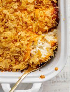 a casserole dish with cheese and other toppings in a white baking dish