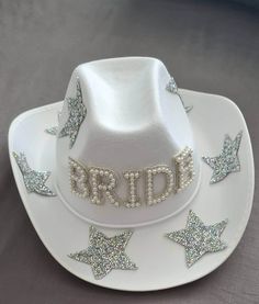 a white cowboy hat with the word brid written in silver glitter stars on it