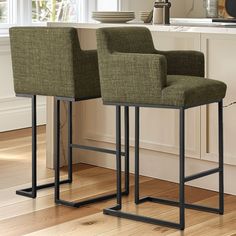 two green chairs sitting on top of a wooden floor next to a white countertop