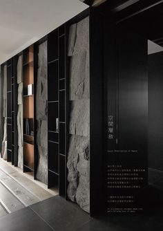 the interior of a building with black walls and stone panels on the wall, along with wooden flooring