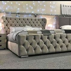 a bed that is sitting in the middle of a room with lights on behind it