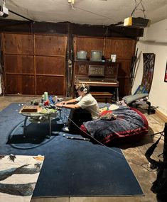 a man sitting on top of a blue rug in front of a tv and piano