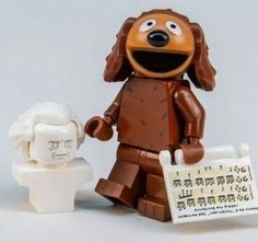 a lego dog holding a sign next to a fake human head and another toy figure