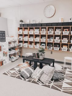 a room filled with lots of books on shelves next to a black table and white chairs