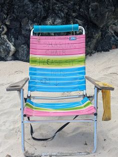 a colorful lawn chair sitting on top of a sandy beach