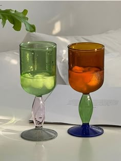 two wine glasses sitting next to each other on top of a white tableclothed surface