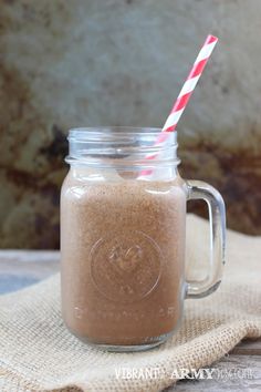 a mason jar filled with brown liquid next to a striped straw on top of a cloth