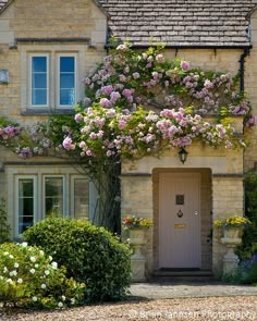 a house with pink flowers growing over the front door