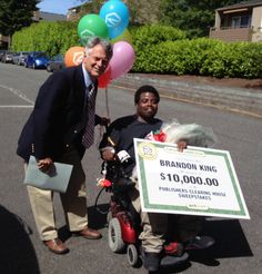 a man on a scooter holding a giant check for $ 10, 000