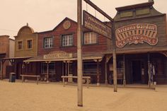 an old western town with wooden buildings on the sides and street signs in front of them