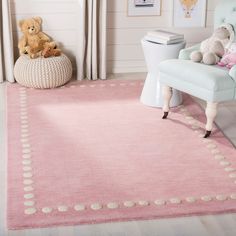 a child's room with a pink rug and teddy bear on the chair in front