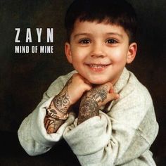 a young boy with tattoos on his arms and chest smiles at the camera while wearing a white hoodie