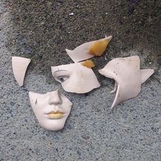 three white masks with yellow noses are on the ground next to each other and one is broken