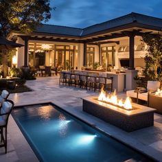 a fire pit in the middle of a patio next to a swimming pool at night