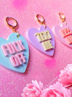 three heart shaped keychains with the words fun off written on them and pink flowers