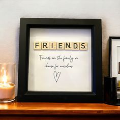 a couple of framed pictures sitting on top of a wooden table next to a candle