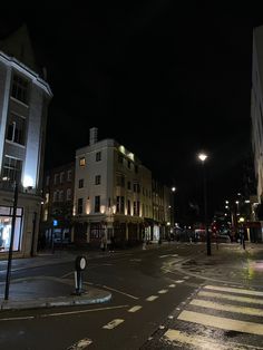 an empty city street at night with no cars or people on the road and buildings in the background