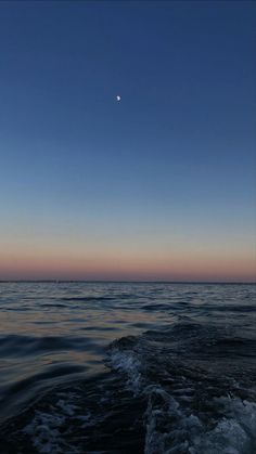 the moon is setting over the ocean as seen from a boat on the water's surface