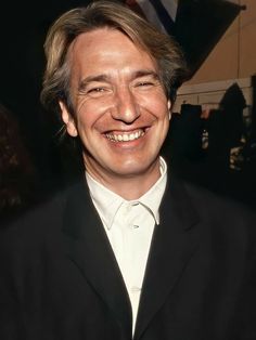 a smiling man in a black suit and white shirt