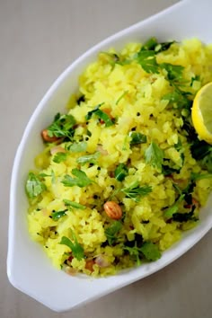 a white bowl filled with yellow rice and garnished with parsley next to a slice of lemon