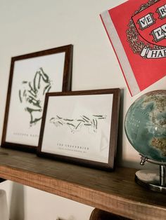 three framed pictures on a mantle with a globe and flag in the corner next to them