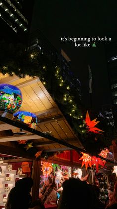 people are standing outside at night with lights on the roof and decorations hanging above them