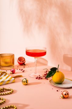 a pink table topped with a glass of wine and a lemon on top of a plate