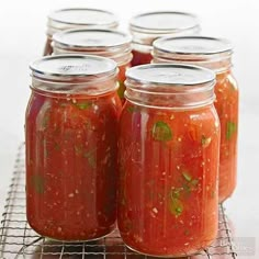 six jars filled with tomato sauce on a cooling rack