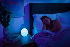 a woman laying in bed next to a night light