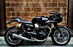 a black motorcycle parked in front of a brick wall