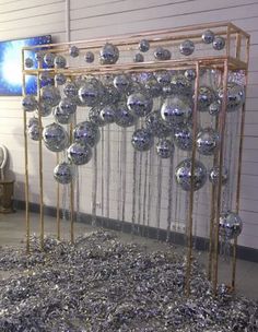 a room filled with lots of shiny silver balls on top of a metal stand next to a white wall