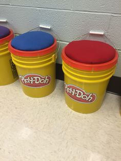 three buckets with play - doh lids are lined up against a wall