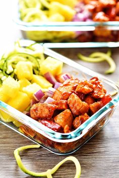 two plastic containers filled with food on top of a wooden table next to sliced vegetables