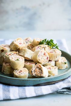 a plate filled with rolls and garnish on top of a table next to a napkin