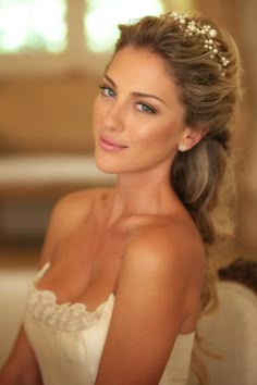 a beautiful woman in a white dress sitting on a couch wearing a tiara with pearls