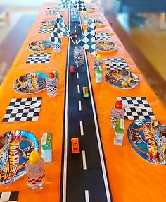 a long table with plates and cups on it is set up for a race car themed birthday party