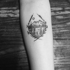 a black and white photo of a mountain tattoo on the left inner arm, with trees in the background