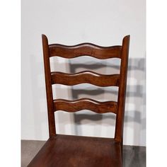 an old wooden chair sitting against a white wall