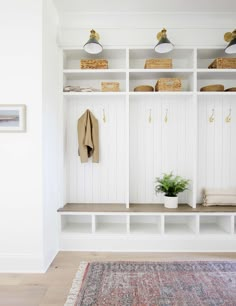 a room with white walls and shelves filled with baskets on top of them, along with a rug in front of it