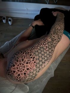 a man laying on top of a bed covered in tattoos