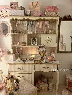 a white desk topped with lots of drawers next to a mirror and dresser filled with boxes