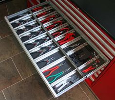 there are many tools in the drawer on the floor next to the tool box and wrenches