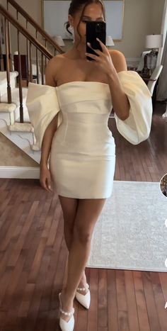 a woman taking a selfie while wearing a white dress and high heeled shoes