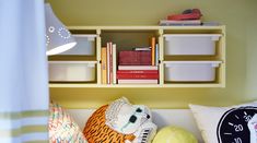 a shelf with books and pillows on it in a child's room, next to a window