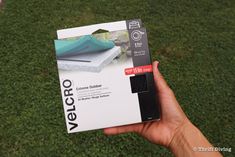 a person holding up a velcro camera in front of the box on grass