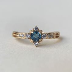 a close up of a ring with a blue stone in the middle and two white diamonds around it