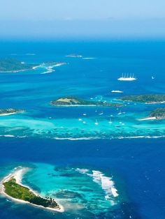 an aerial view of several small islands in the middle of the ocean with boats on them