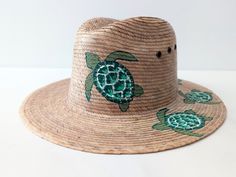 This listing is for one piece of this beautiful handmade straw hats with turtle paint. All the work is done by hand. They are prefect to add to your closet for your favorite dress, providing shade from the warm summer sun. You will get the exact same piece shown on the pictures when selected the style number. These products are brand new. Measurements :  2.5 inches rim 4.5 inches tall, comes with an elastic band for added comfort. 54 cm inside. please see pictures for measurements. I love  Mexico celebrates the native crafts of Mexico and the artists that produce them, enabling them and their communities to get recognized for their talented work and achieve economic stability for their families. Whimsical Fedora Hat For Beach, Whimsical Fedora Beach Hat, Whimsical Adjustable Beach Hat, Whimsical Fedora For Beach, Whimsical Beach Hat, Whimsical Short Brim Beach Hat, Artisan Palm Leaf Sun Hat For Beach, Adjustable Whimsical Straw Hat For Vacation, Whimsical Adjustable Straw Hat For Vacation