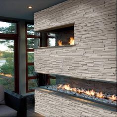 a fire place in the middle of a living room next to a couch and window