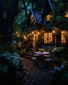 a table and chairs in front of a house with lights on it's windows